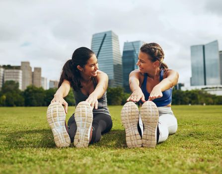 Getting warmed up is better with a partner. Full length shot of two attractive young sportswomen doing stretch exercises together outdoors in the city.