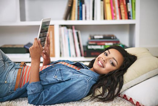 Staying connected has never been easier. Portrait of a young woman using her digital tablet at home.