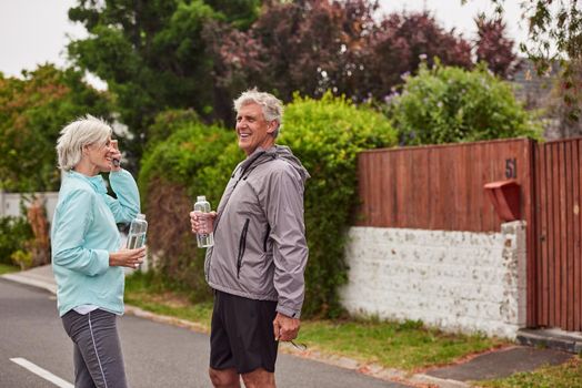 We got our exercise in for the day. Cropped shot of a cheerful senior couple drinking water after having a jog together outside in a suburb.