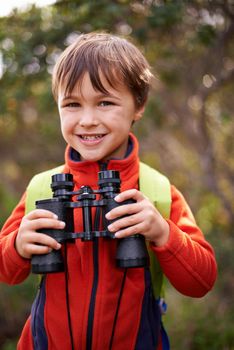 On the lookout for my next adventure. Portrait of a happy young boy out in the woods with a pair of binoculars.