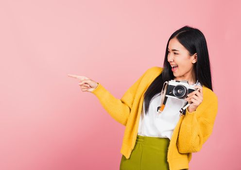 woman teen excited smiling holding vintage photo camera and pointing finger