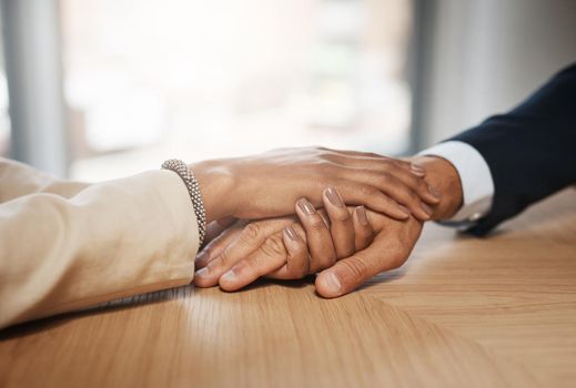 Your kindness can change worlds. Closeup shot of two unrecognizable businesspeople holding hands in an office.