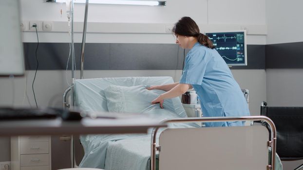 Woman nurse making bed in hospital ward for healthcare