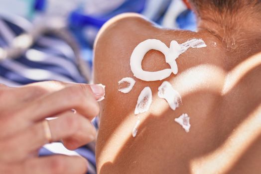 Woman apply protective sunscreen on the boy's shoulders skin