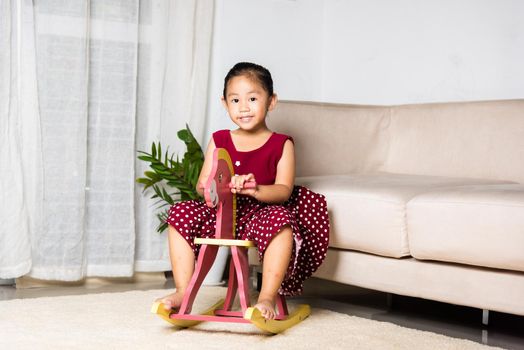 Asian cute little girl swinging riding toy horse