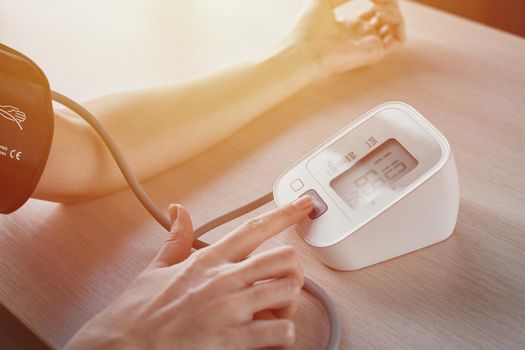 Woman measuring blood pressure with electric digital tonometer. Healthcare and medicine concept
