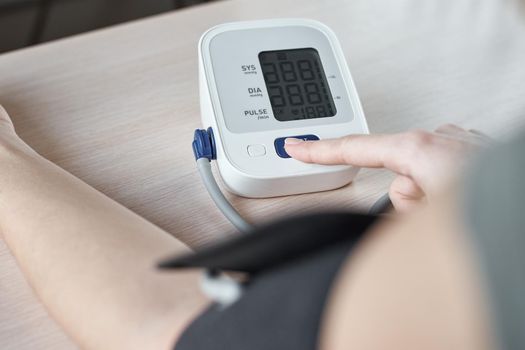 Woman measuring blood pressure with an electric digital tonometer. Healthcare and medicine concept