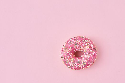 donats decorated sprinkles and icing on a pink background. Creative and minimalis food concept, top view flat lay