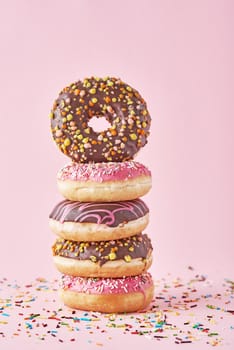 Stack of colorful donuts decorated on a pink background
