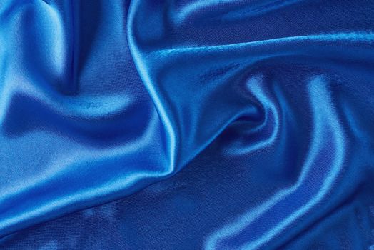 Blue silk background with a folds. Abstract texture of rippled satin surface
