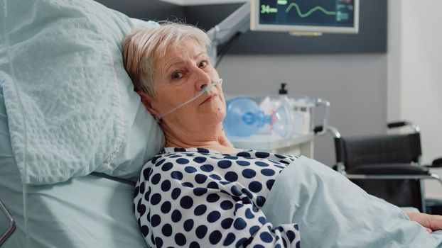 Portrait of old patient laying in bed with nasal oxygen tube