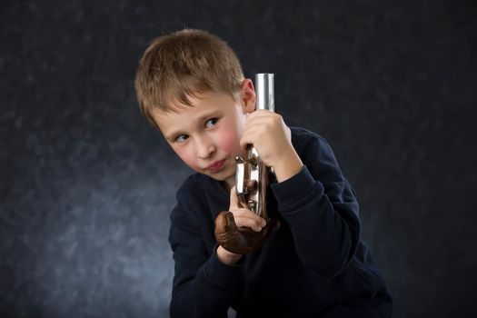 Boy with a gun. The child plays with the weapon. Six seven year old toddler with retro boob