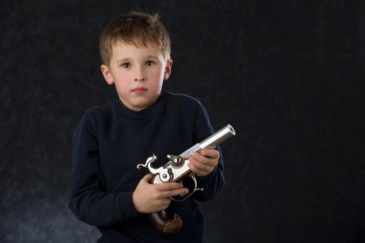 Boy with a gun. The child plays with the weapon. Six seven year old toddler with retro boob