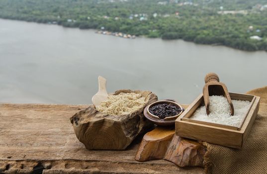 Various types of rice : Brown rice, Jasmine rice and Riceberry on old wooden table with natural scenery. 