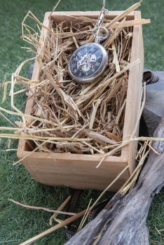A retro pocket watch on straw background in wooden box. 