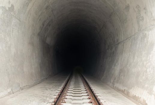 Railway track leading lines into the dark train tunnel entrance. 