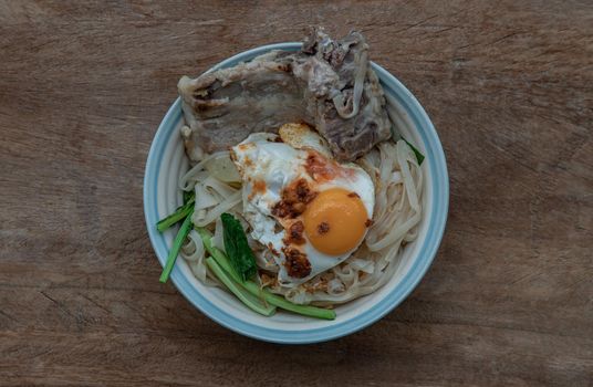 Thin rice noodles soup with Pork ribs, Fried egg and vegetable sprinkle with smoked shrimp paste chili dip.