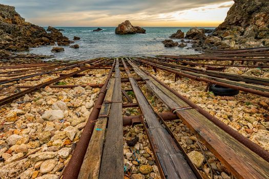 Scenic view from the shore with rails for transporting boats and big rocks