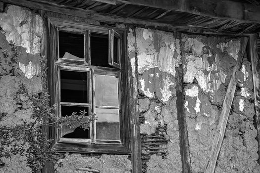 Black and white image of broken windows abandoned rustic house