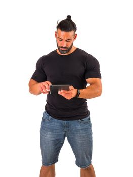 Attractive muscular man using electronic tablet in studio