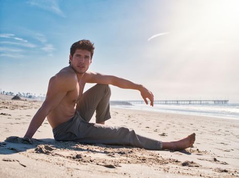 Handsome young man on beach in a sunny day, sitting