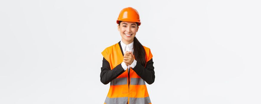 Thankful successful asian female architect greet investors or clients at construction area, wearing safety helmet and jacket, shaking clenched hands in appreciation, being grateful for trust