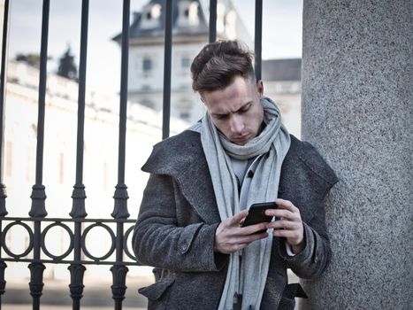 Handsome trendy man typing on cell phone