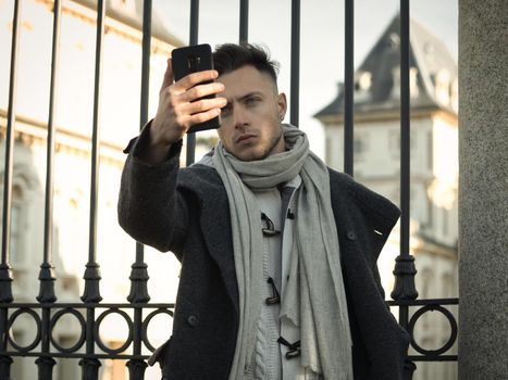 Attractive man using cell phone to take photo or selfie photo outdoors