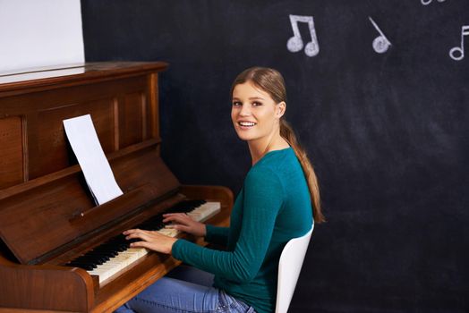 Using illustrations to teach her students. Shot of a woman playing the piano against a background of musical notes.