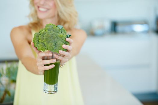 Keep you body happy with one of these. Shot of a happy woman holding a broccoli shake.