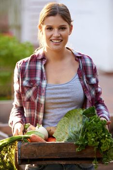 Harvested with happiness. Portrait of a happy young woman holding a crate full of freshly picked vegetables.