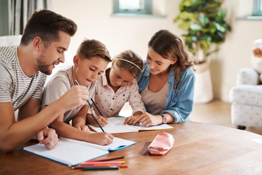 Shot of a happy young family of four doing homework together.