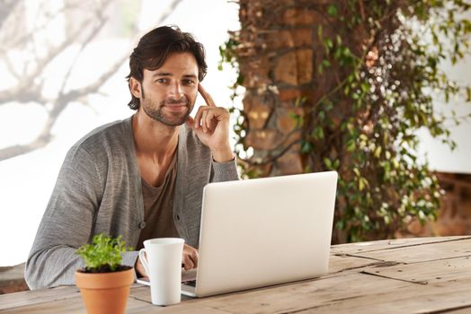 I always start off my morning catching up online. Portrait of a handsome young man using his laptop outdoors.