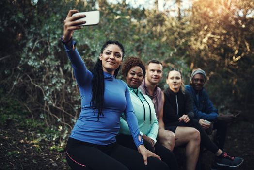 We love taking selfies during our workout. Cropped shot of a sporty young group of friends taking a selfie while taking a break during a workout in the forest.
