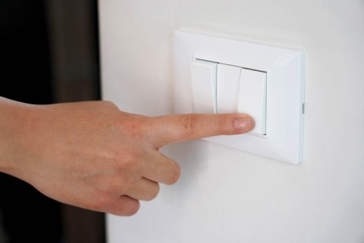 Energy saving. Female finger is turn off on lighting switch.