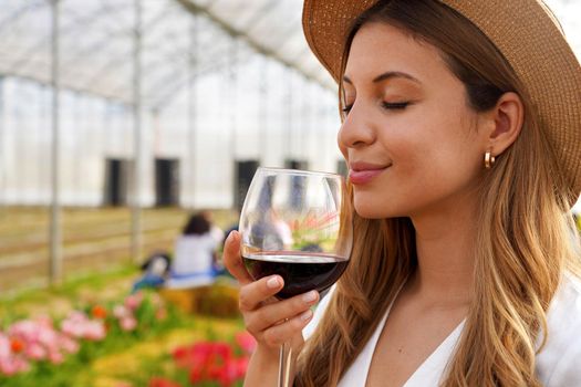 Close-up of beautiful woman smelling red wine from glass with closed eyes