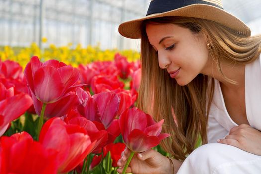 Happy woman with straw hat smelling tulips on farm