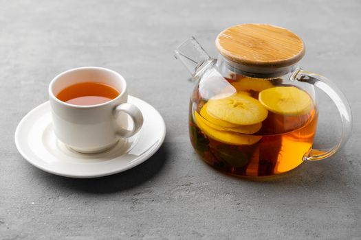 Glass teapot with fruit tea on gray background