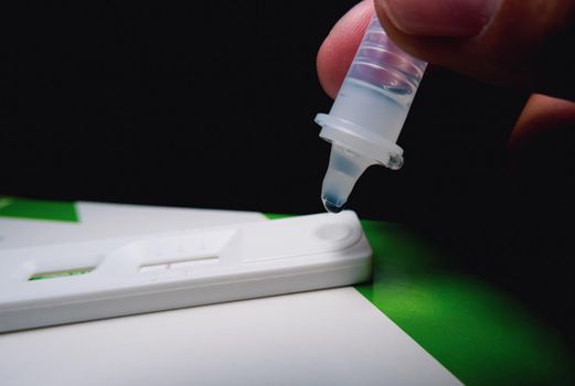 Own hand placing the droplet secretions sample into the SARS CoV-2 Rapid antigen test kit (ATK) with the extraction tube,Coronavirus infectious protective concept
