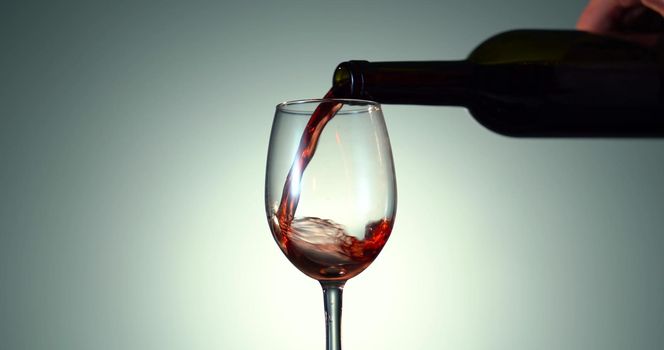 Pouring Rose Wine from a Transparent Bottle into the glass on the White Background. Alcohol concept