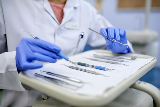 Dental tools at the ready. Closeup shot of an unrecognisable dentist working with a tray of surgical instruments.