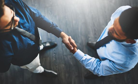 Its a done deal. Shot of two businessmen shaking hands in an office.