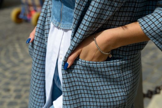 beautiful female hands with blue manicure and element of stylish checkered coat