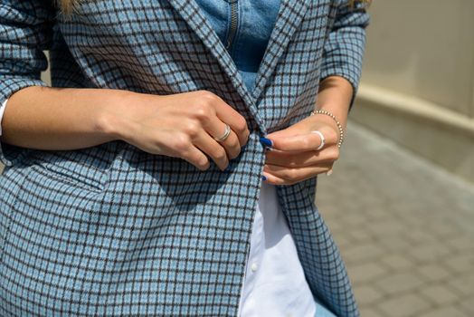 beautiful female hands with blue manicure and element of stylish checkered coat