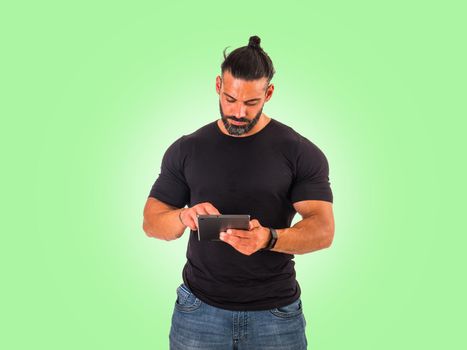 Attractive muscular man using electronic tablet in studio