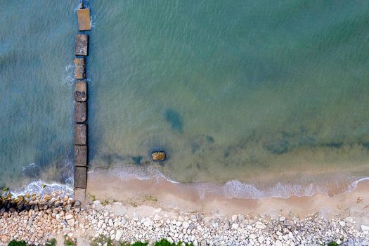 Aerial top view from drone to the seashore with old concrete pier