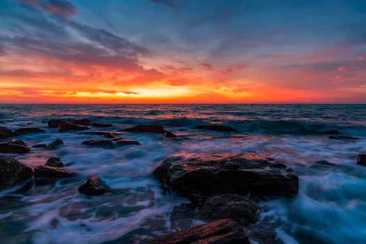 Beautiful motion blur sea waves over the rocks before sunrise