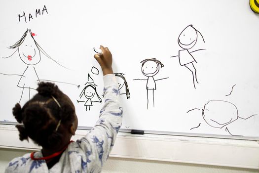 A five-year-old girl draws a family on the blackboard. Charitable Center for Support and Adaptation of Refugee and Migrant Children "The Same Children"