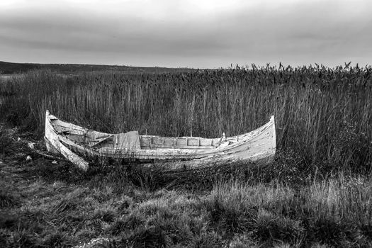 An abandoned old wooden fishing boat on the beach. Black and white