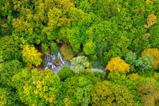 Aerial view from drone of beauty waterfall between trees in autumn